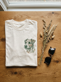 Gefaltetes cremefarbenes T-Shirt mit Line-Art-Portrait auf der Brust